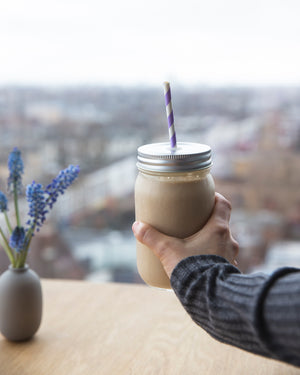
                  
                    Load image into Gallery viewer, Hand holding a Herbalife Formula 1 breakfast shake in a mason jar with a paper straw, overlooking a city skyline, symbolising a healthy start to the day.
                  
                