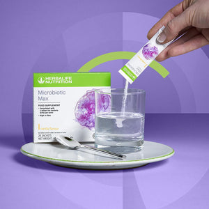 
                  
                    Load image into Gallery viewer, sachet of Herbalife Nutrition Microbiotic Max being poured into glass of water with product box next to it
                  
                